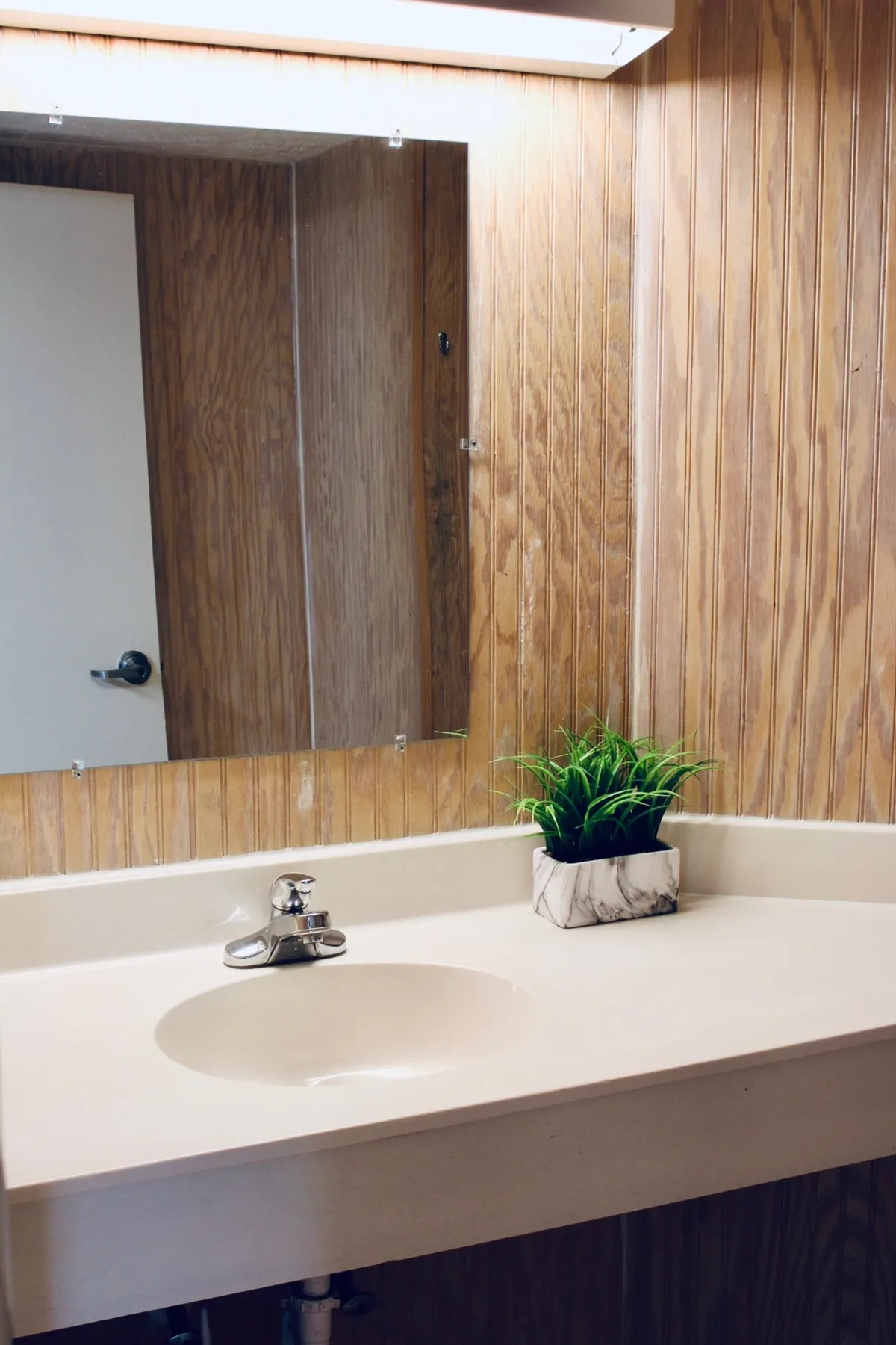 This image showcases a bright, modern bathroom interior. The foreground focuses on a sleek sink and mirror, with a potted plant adding a touch of greenery and freshness. The calm, well-lit atmosphere suggests a space designed for both grooming and relaxation, offering a glimpse of the modern essentials provided.