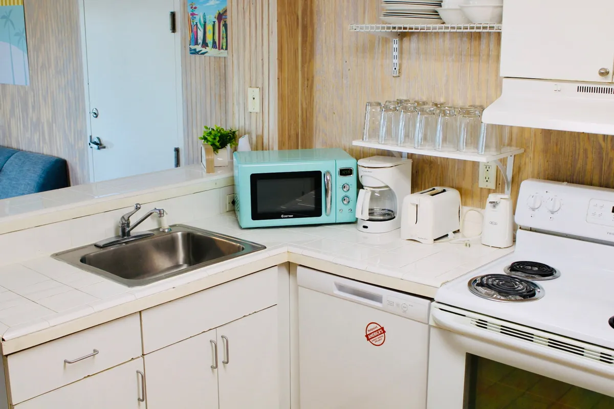 This image shows a cozy kitchenette area featuring a microwave, coffee maker, toaster, stove, and sink. The space is practical and inviting, with all the key appliances and essentials clearly visible, ideal for preparing meals or snacks.